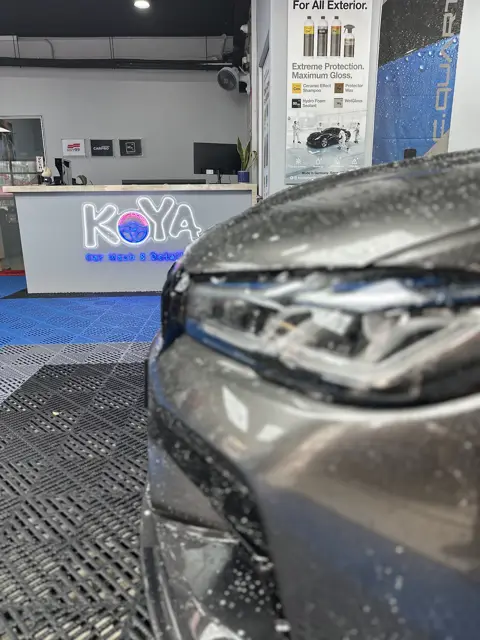 Grey car front under snow foam at KOYA